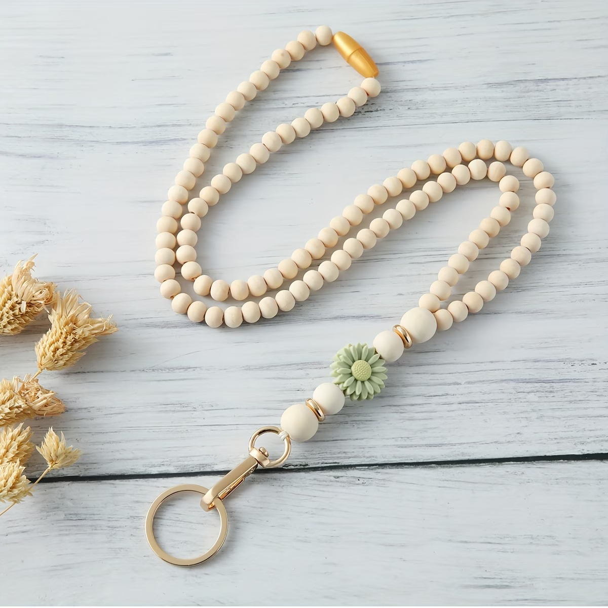 Handcrafted beaded lanyard featuring a soft sage silicone daisy focal, natural beechwood beads, and gold accents with a safety breakaway clasp by Woodland Beads & Co.