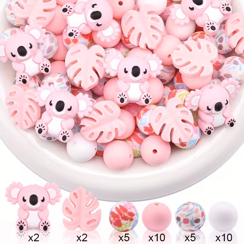 A product showcase for a 34-piece DIY silicone bead kit. The top half of the image shows a white bowl filled with a mix of light pink koala beads, pink monstera leaf beads, solid pink and white round beads, and floral-patterned round beads. The bottom half displays a clean row of the individual bead styles alongside their quantities: 2 pink koalas, 2 pink tropical leaves, 5 red floral round beads, 10 solid pink round beads, 5 multi-colored abstract floral round beads, and 10 solid white round beads.